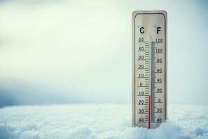Thermometer on snow shows low temperatures under zero. Low temperatures in degrees Celsius and fahrenheit. Cold winter weather ten under zero. photo