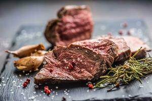 Juicy beef steak with spices and herbs on wooden cutting board photo