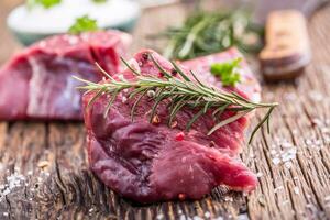 Raw beef meat. Raw beef tenderloin steak on a cutting board with rosemary pepper salt in other positions. photo