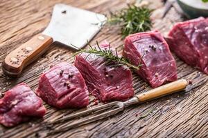 Raw beef meat. Raw beef tenderloin steak on a cutting board with rosemary pepper salt in other positions. photo