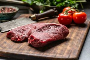 Two beef rump steaks with herbs tomatoes salt and spices on butcher board photo