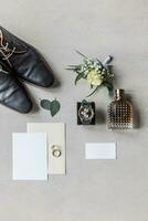 Top view of groom's preparation kit for the wedding with shoes, envelopes, wedding rings and perfume photo