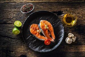 Salmon raw steaks rosemary tomatoes mushroom lime olive oil and spices. photo