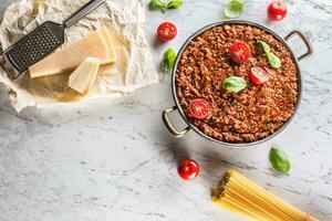 Classic italian bolognese sauce with ingredients pasta spaghetti olive oil tomatoes basil and parmesan cheese photo