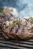 Juicy beef rib eye steaks on the grill with rosemary salt and spices photo