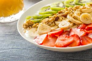 Healthy breakfast served with plate of yogurt muesli kiwi strawberries and banana photo