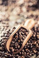 Wooden scoop full of coffee beans on old oak table photo
