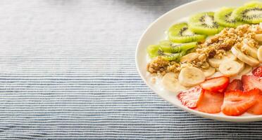 Healthy breakfast served with plate of yogurt muesli kiwi strawberries and banana photo