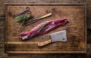 Raw beef meat. Raw beef tenderloin steak on a cutting board with rosemary pepper salt in other positions. photo