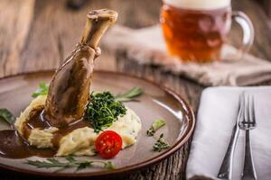 Lamb shank.Confit lamb shank with mashed potatoes spinach and draft beer in pub or restaurant photo