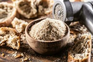 A wooden bowl full of breadcrumbs and old dry bread around photo