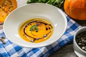 Pumpkin cream soup with seeds and parsley on kitchen table photo