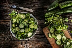 Sliced cucumber on a plate with parsley herb on rustic oak wood. photo