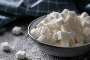 White sugar cubes in a blue bowl on the table photo