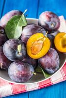 Plums. Fresh juicy plums in a bowl on a wooden or concrete board photo