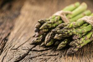 Bunch of fresh asparagus on rustic oak table photo