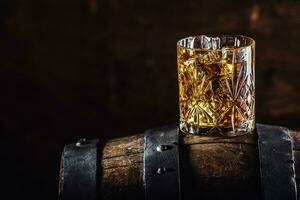 A glass of whiskey on an old wooden barrel photo