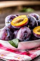 Plums. Fresh juicy plums in a bowl on a wooden or concrete board photo