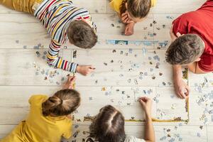 parte superior ver de un familia montaje rompecabezas en el piso a hogar foto