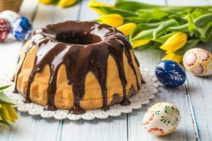 Delicious holiday slovak and czech cake babovka with chocolate glaze. Easter decorations - spring tulips and eggs photo