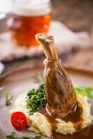 Lamb shank.Confit lamb shank with mashed potatoes spinach and draft beer in pub or restaurant photo