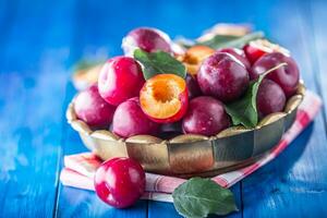 Plums. Fresh juicy plums in a bowl on a wooden or concrete board photo