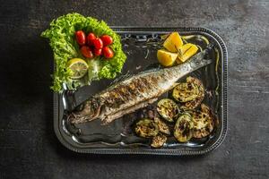 Roasted fish on dish with fresh and grilled vegetable photo