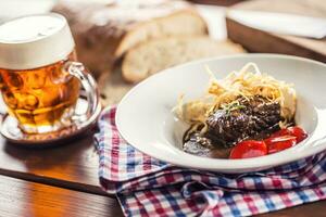 Confit beef steak with sauce fried onion bread draft beer and decoration in pub or restaurant photo
