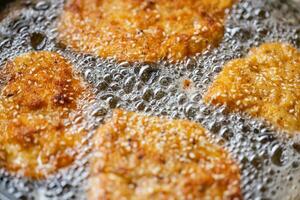 Detail of bubbles in frying oil as schnitzels fry in the pan photo