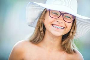Happy smiling girl with dental braces and glasses. Young cute caucasian blond girl wearing teeth braces and glasses photo