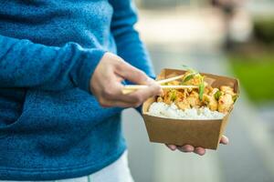 Young man's hands holding lunch in a box of recycled paper photo