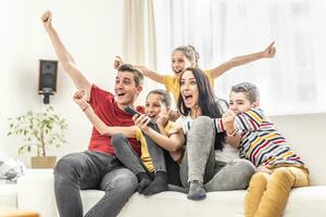 Enthusiastic family of five cheers at home watching sports on TV photo