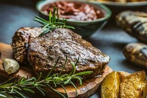 Beef grilled steaks with barbecue sauce roasted potatoes and rosemary photo