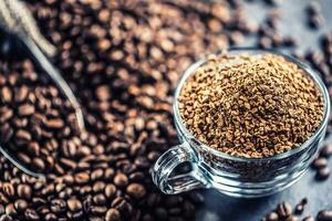 Granules of instant coffee in glass cup and coffee beans. photo