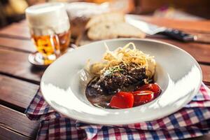 Confit beef steak with sauce fried onion bread draft beer and decoration in pub or restaurant photo