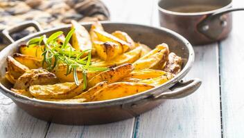 Roasted potatoes in a frying pan on wooden board photo