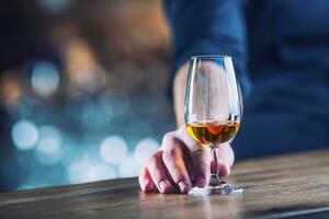 Alcoholism. Hand alcoholic or barman and drink the distillate brandy or cognac photo