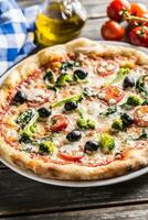 Irtalian pizza with broccoli spinach tomatoes olives and mozzarela or parmesan cheese. Mediterranean vegetarian meal photo