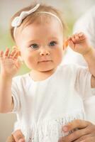 Adorable small toddler girl with blue eyes and blonde hairwith her arms raised to her head photo