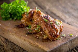 Chicken wings grilled BBQ  parsley herb and sesame on wooden board. photo