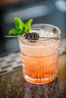 Cocktail drink bramble with black berries and mint at barcounter in night club or restaurant photo