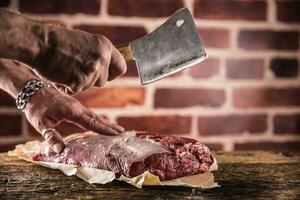 Butcher man hands cutting raw beef steak in butchery photo