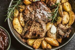 Beef grilled steaks with barbecue sauce roasted potatoes and rosemary photo