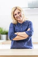 Confident woman in mid age stands with arms crossed on her chest photo