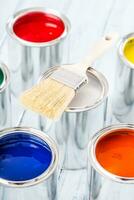 Close-up brush lying on multicolored paint cans. photo