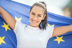 sonriente hermosa mujer participación un UE bandera mirando a el cámara foto