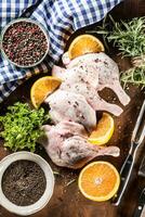 Top of view raw duck legs with oranges and herbs. photo