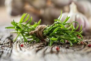 Fresh rosemary and garlic cloves with spices on old wooden table photo