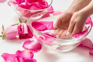 Female hands and bowl of spa water with pink roses and  petals photo