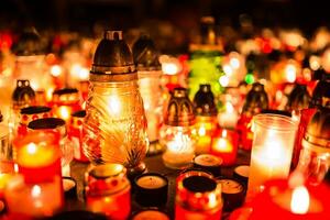 muchos ardiente velas en el cementerio a noche en el ocasión almas de el fallecido foto